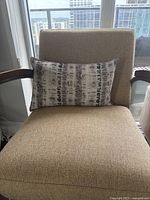 Grey and black patterned rectangular pillow on beige armchair