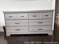 Front view of grey dresser showing six drawers and hardware