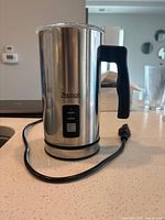 Zeppoli heated milk frother showing exterior with handle, buttons, and power cord on kitchen counter.