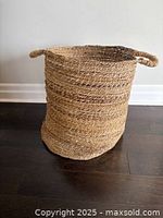 Side view of the natural jute laundry hamper showing woven texture and one handle.