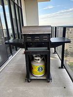 Front view of Master Chef 2 burner propane barbecue with middle propane tank inside storage area and foldable side shelves.