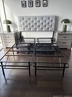 Front view of queen metal bed frame and grey tufted headboard between two nightstands