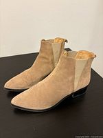 Side and angled view of camel tone suede ankle boots showing suede texture, low heel, and elastic side panel
