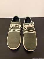 Front view of the pair of olive green knit sneakers with white soles and laces tied on top