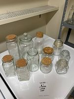 Group of 11 assorted glass jars on a surface with a sign showing lot number 101