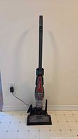 Full view of the Bissell Powerswift Ion XRT vacuum standing upright on floor next to a wall outlet with power cord plugged in.