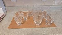 Set of 10 diamond cut crystal glass tumblers arranged on counter showing 6 medium and 4 small sizes.