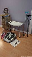 Full lot with shower chair, two canes, rolling shopping cart, foot massager with remote and manual on floor seen