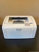 Front view of the HP LaserJet 1018 printer showing the paper output area, HP branding, and control panel area.