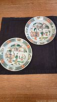Two white porcelain plates side by side on black cloth showing overall lot contents