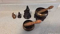 Two Tibetan meditation bowls with wooden mallets and three small Buddha statues including laughing Buddha and seated Buddha figures