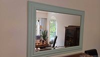 Full view of rectangular mirror mounted on a wall reflecting room interior.