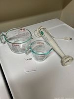 Lot showing Braun hand immersion blender alongside two Pyrex glass measuring cups on a white surface.