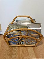 Front view of the rattan magazine rack holding assorted art books of different sizes and cover designs
