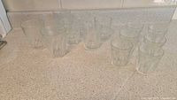 Overview of 14 faceted juice glasses arranged on a countertop showing three distinct size sets.