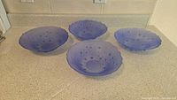 Four blue glass bowls displayed on countertop, showing size and shape with dotted pattern