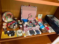 Photo of sewing and craft supplies displayed on wooden shelf, showing thread spools, embroidery floss, buttons, yarn, and storage boxes with supplies.