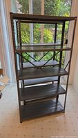 Full front view of one grey metal shelving unit showing five slatted shelves and metal frame.