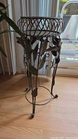 Front view of the full metal plant stand showing floral design and twisted metal circular top.