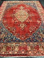Full view of rug showing red field, ivory central medallion and floral border