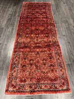 Full-length overhead view of red runner rug with all-over pattern on dark wood floor