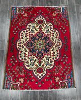 Top down view of the entire Tabriz rug with floral medallion pattern on red background, highlighting overall design and condition.