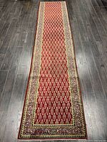 Full view of the Persian Tabriz runner rug laid out on dark flooring showing the overall size and pattern.