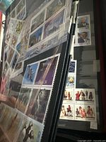 Photo showing a binder with multiple black pages containing unused colorful Canadian stamps including birds, landscapes, and historical figures in mint condition.