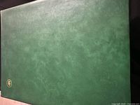 Closed green mottled binder with gold emblem on bottom corner