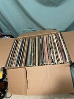 Full box filled with many vinyl records visible from the top view