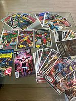 Photo showing a variety of comic books including 2099 Unlimited, The Outsiders, The Bombast, and others arranged on a glass surface.