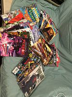 Total comic book collection arranged overlapping on fabric surface showing variety of titles and cover art