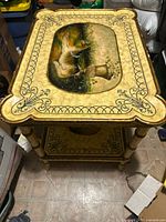 Top view of the hand painted coffee table showing the bear and floral urn artwork with decorative border and visible surface scratches and wrinkles.