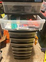 Full view of the multi-drawer plastic organizer with some drawers opened showing assorted office supplies including pens, sticky notes, and rulers.