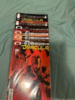 Photo showing all six issues of Sword of Dracula comic books stacked and in plastic protective sleeves on fabric surface.