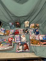 Photo of entire Ty Beanie Babies collection showing multiple bears in both original blister packaging and acrylic display cases on a blue cloth background.