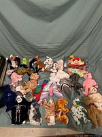 Photo showing entire collection of assorted TY Beanie Babies plush toys laid out on gray fabric background.