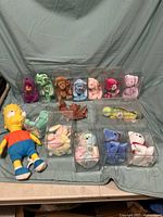 Front view of the Ty Beanie Babies collection arranged with the Bart Simpson plush on fabric backdrop