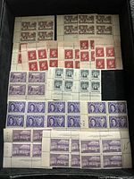 Photo of various unused Canadian postage stamps in blocks and sheets with different colors and designs