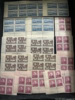 Photo of multiple blocks and strips of unused Canadian postage stamps in blue, brown, and purple