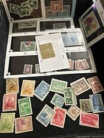 View of multiple Chinese stamps both loose and in an album, showing variety in design and color.