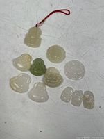Overview of all 11 carved jade pieces in various shapes and shades including white and greenish tones on a white surface.