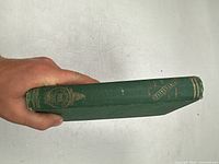 Photo of the book spine showing title and author with green cloth cover and gold embossing