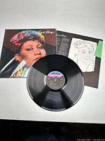Aretha Franklin album cover with colorful portrait by Andy Warhol, vinyl record and lyric insert laid out flat on white background.