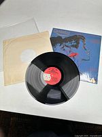 Photo of the Querelle vinyl record outside of its protective sleeve, showing cover art featuring Andy Warhol style pop art illustration of two faces.