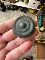Close-up of the top face of the small bronze cymbal showing concentric raised rings and central knob with greenish patina.