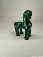 Full view of archaic green glazed porcelain horse figurine on neutral background
