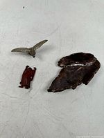 Photo of the three items together showing the pottery piece, wooden Buddha figurine, and metal eagle figurine on a white background
