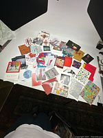 Wide overview photo showing a large pile of assorted souvenir and gallery postcards spread out on a table.