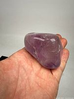 Polished large amethyst specimen held in hand showing size and coloration.